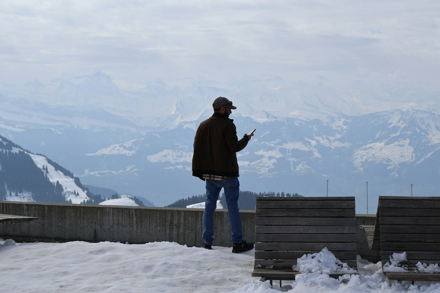 Frontalier consultant son téléphone devant les montagnes suisses
